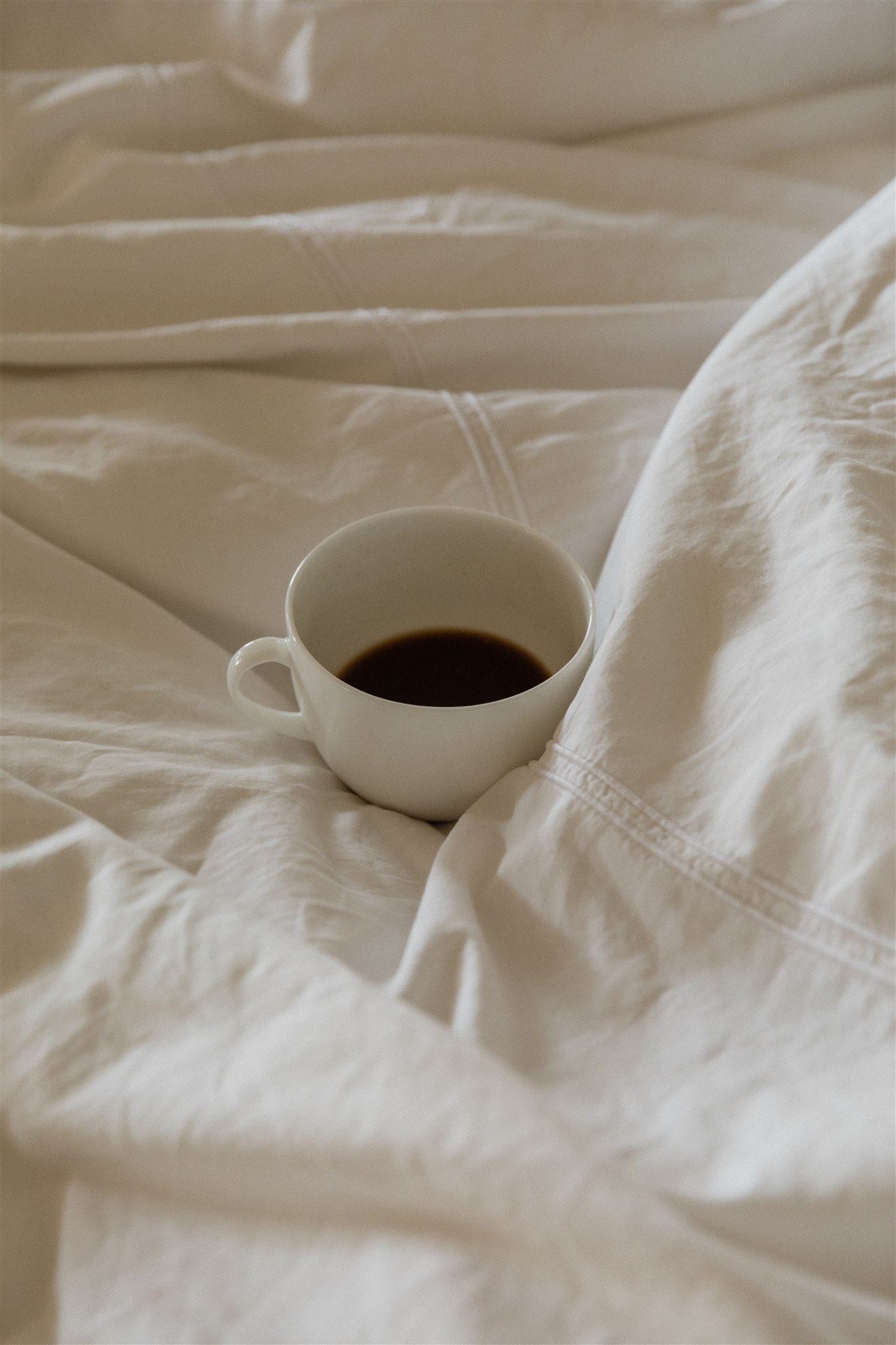 white coffee mug sitting on white linen